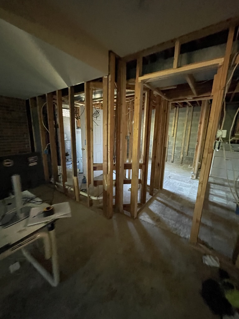 Framing and utility area before drywall installation, showing the basement structure during the construction phase