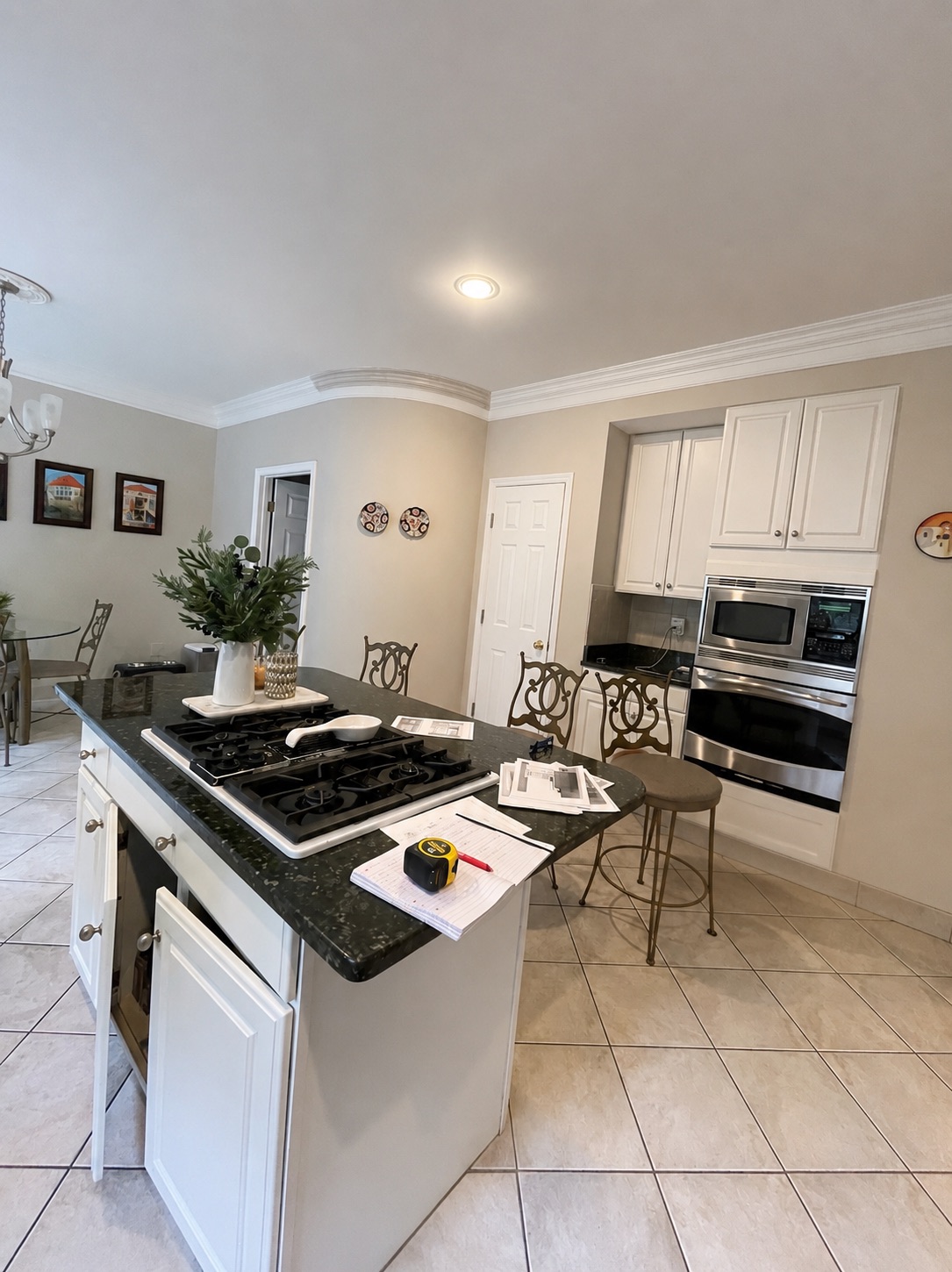 Original center island and cooktop with dark granite counters and white traditional cabinetry