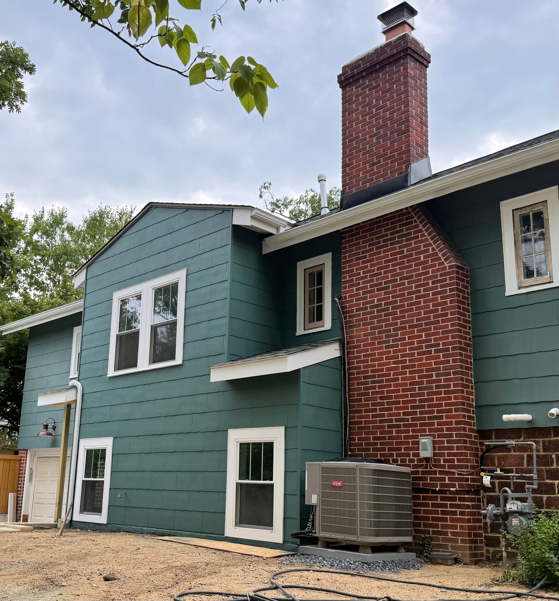 Completed residential addition with green siding and trim matched to the existing home