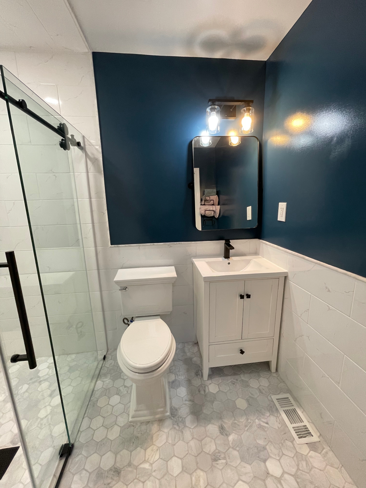 Completed bathroom with curbless walk-in shower, frameless glass enclosure, grab bars, and accessibility features