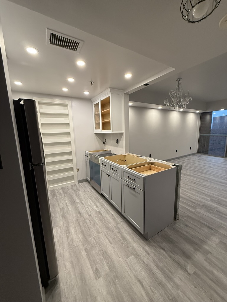 Construction phase — new cabinetry, LVP flooring, and recessed lighting installed