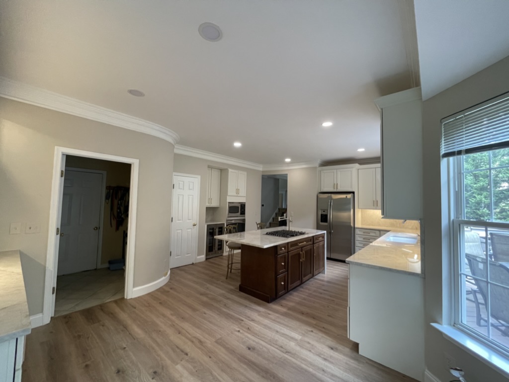 Renovated kitchen entry view featuring luxury vinyl plank flooring, new custom cabinetry, and waterfall island