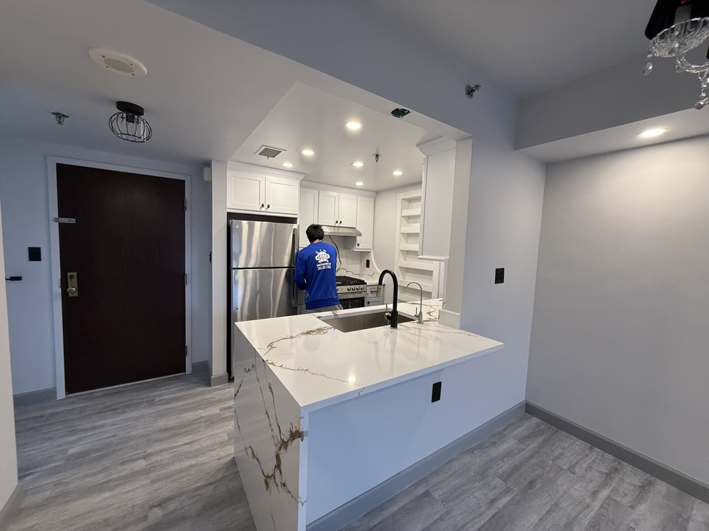 Appliance, range hood, and waterfall quartz island installation in progress