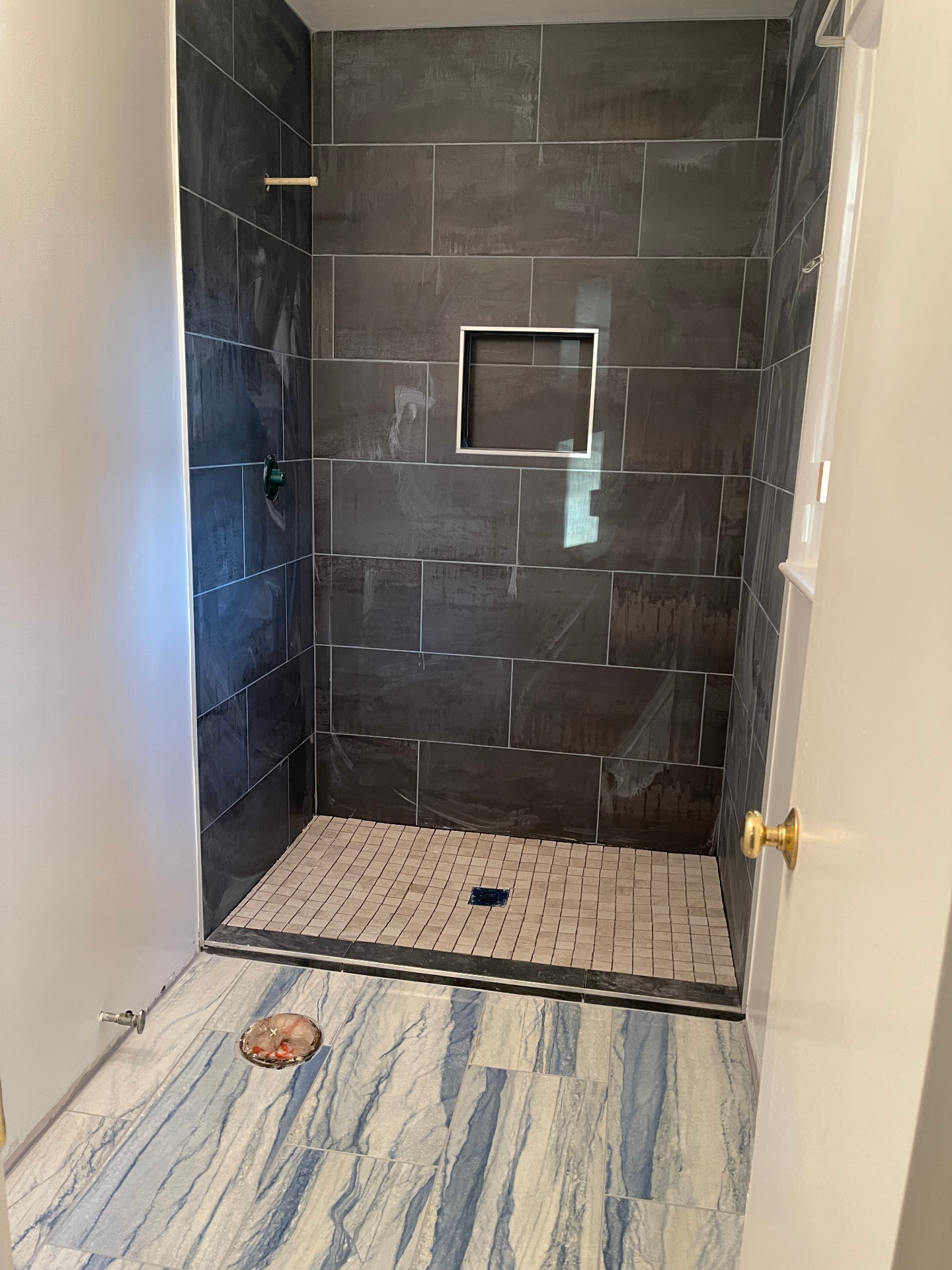 Shower and floor tile nearing completion with recessed niche