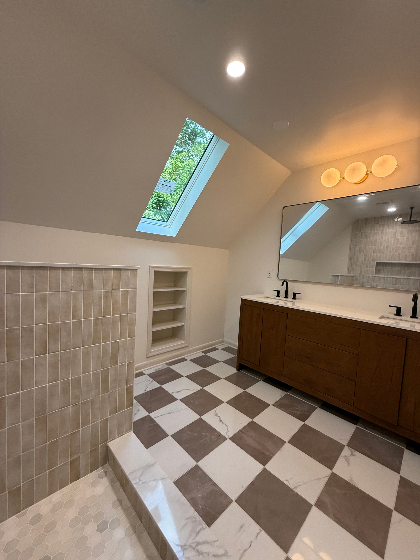 Completed bathroom with skylight, custom tiled shower, niche, and double vanity