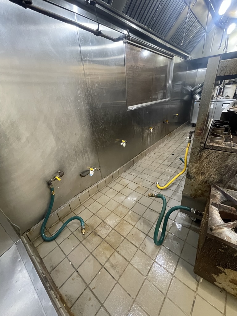 BEFORE — Existing commercial kitchen wall behind the cooking line before repair.