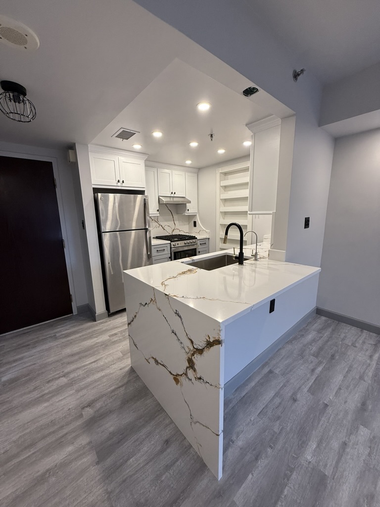 Finished waterfall quartz island, new cabinetry, range, and modern lighting