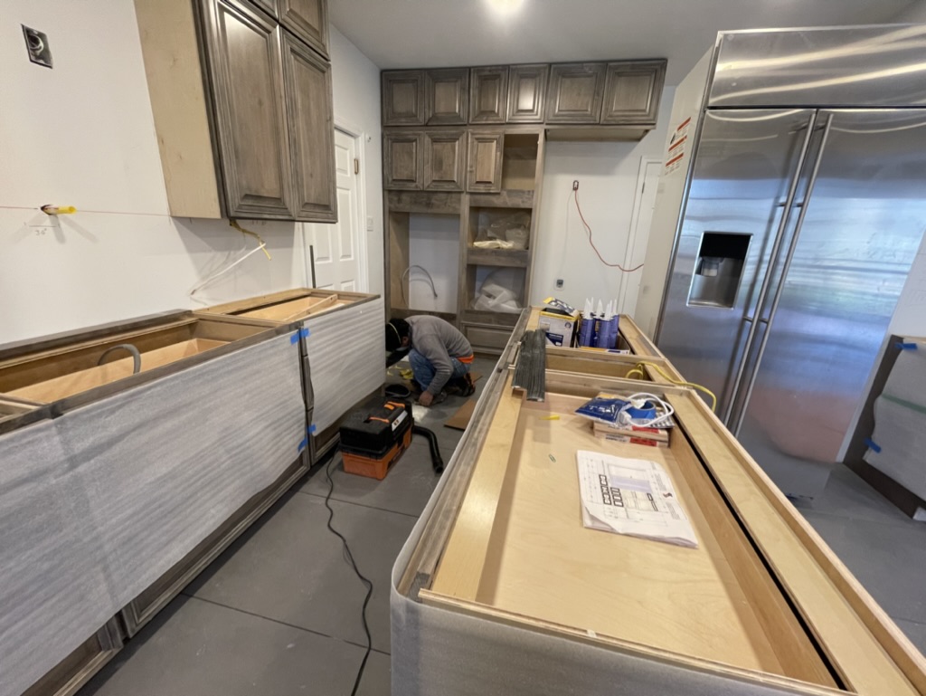 Island construction and layout development — ESM team setting cabinetry, verifying appliance placement, and performing finish carpentry prior to countertops
