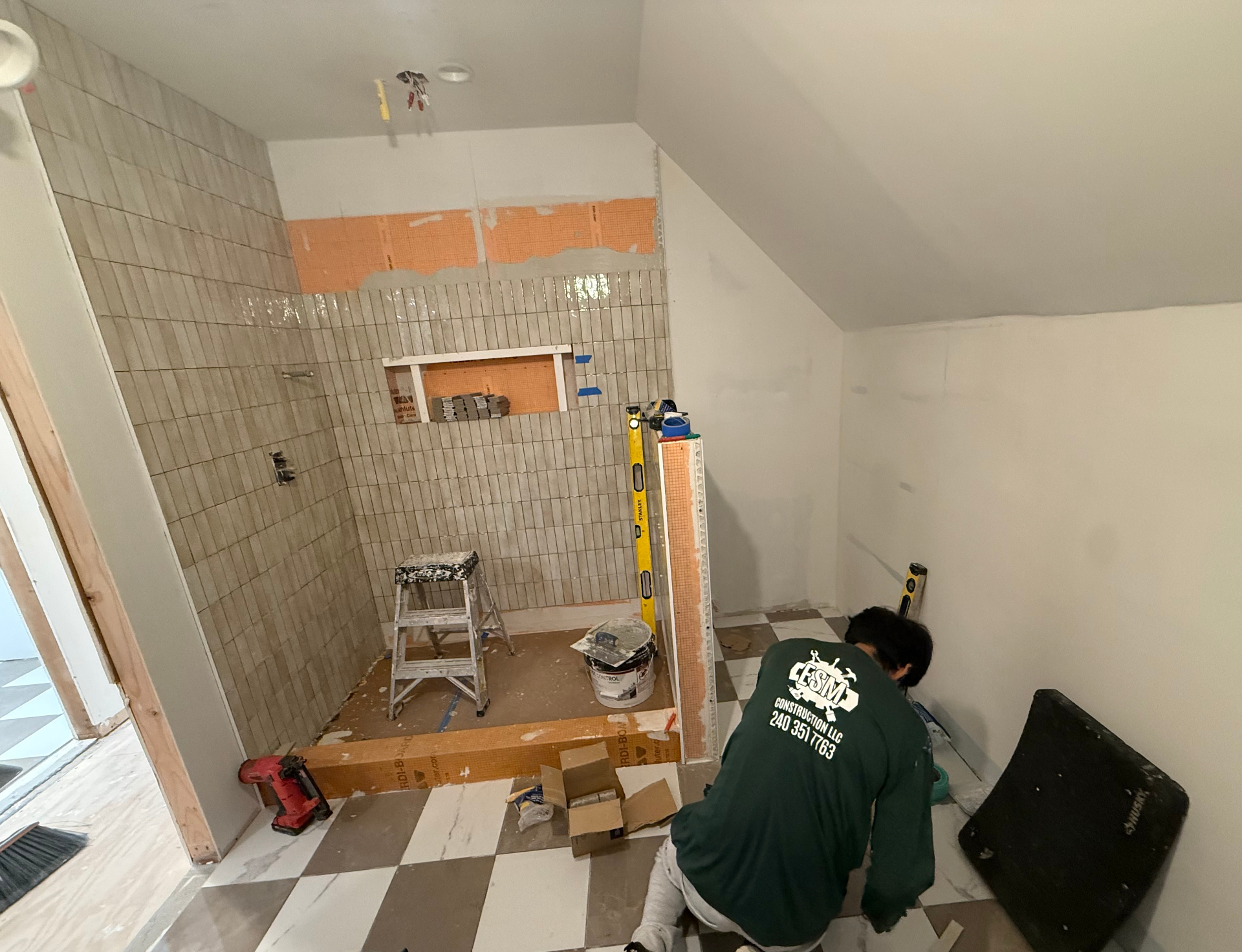 Bathroom conversion in progress — shower tile installation and floor work