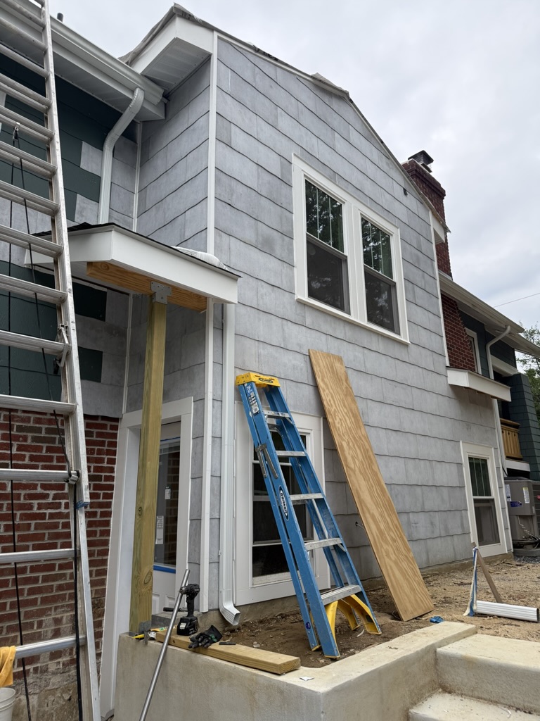Exterior finishing — siding, trim, gutters, and roof details installed