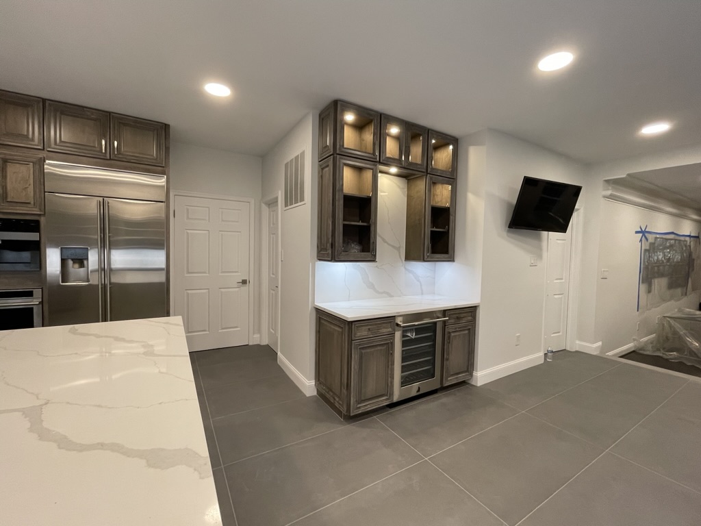 Completed beverage bar with built-in refrigerator, wine cooler, and quartz backsplash