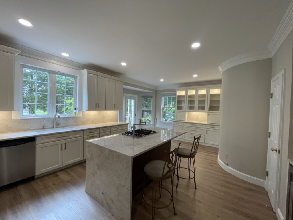Final wide view of the completed bright custom kitchen with waterfall island, quartz countertops, custom cabinetry, and upgraded lighting