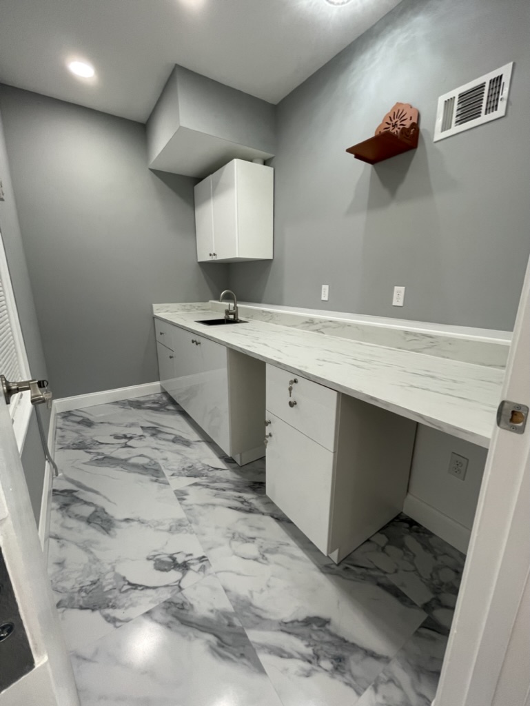 Cabinetry and countertop work area with sink and upper storage